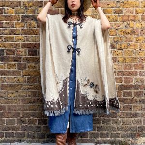 Model wearing late 1990s embroidered poncho with fringe hem and folk floral design