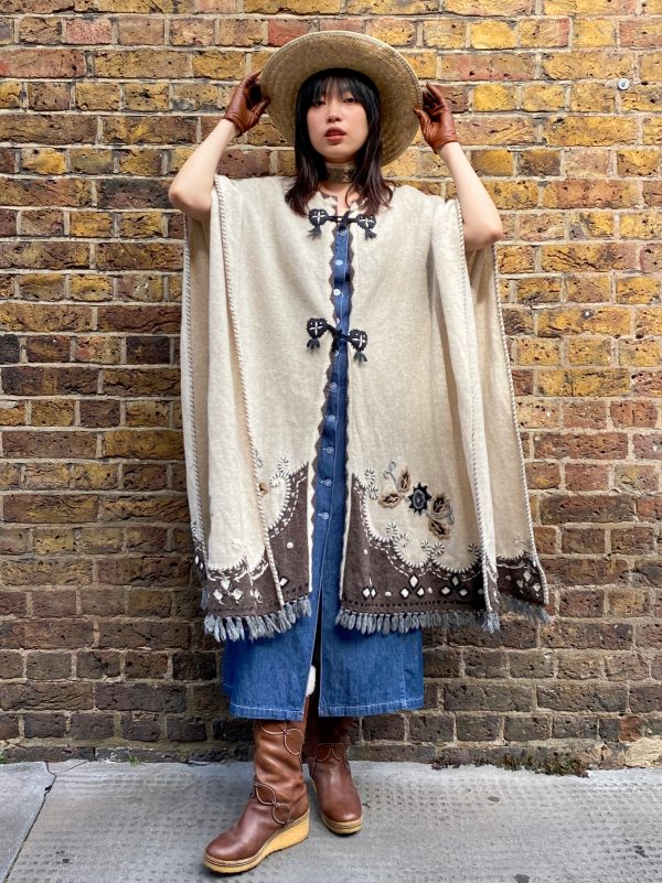 Model wearing late 1990s embroidered poncho with fringe hem and folk floral design