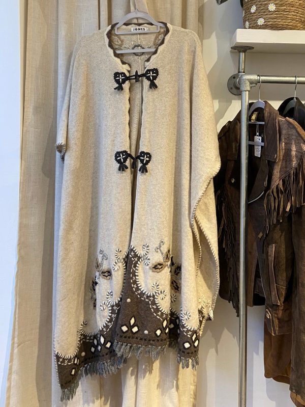 Full front view of late 1990s embroidered poncho with fringe hem and floral detailing