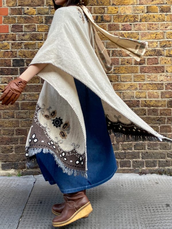 Model wearing late 1990s embroidered poncho with fringe hem and folk floral design