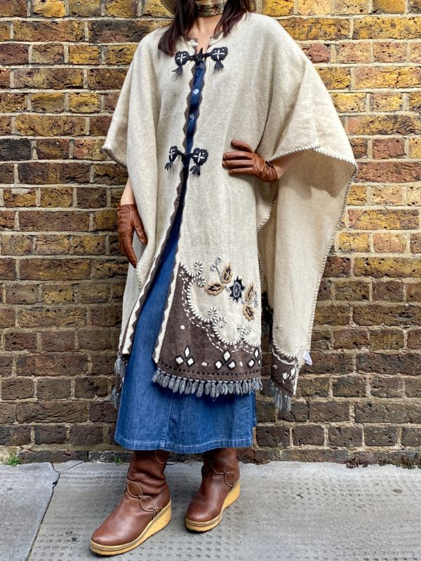 Model wearing late 1990s embroidered poncho with fringe hem and folk floral design