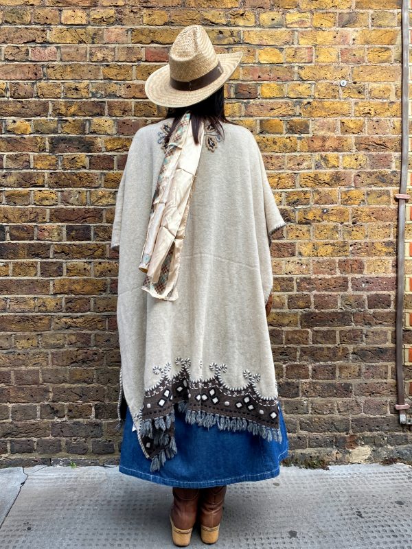 Model wearing late 1990s embroidered poncho with fringe hem and folk floral design
