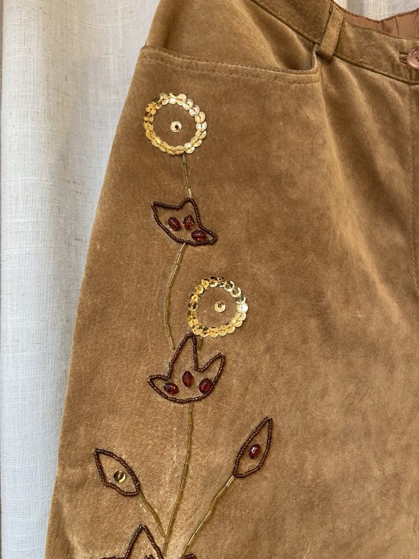 Close-up of vintage suede trousers with floral embroidery and high waist