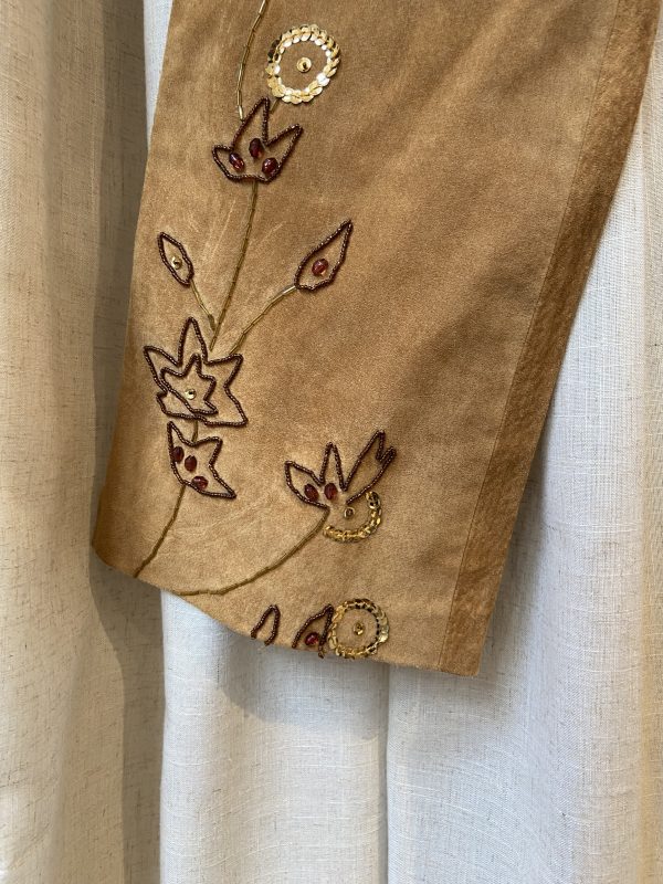 Close-up of vintage suede trousers with floral embroidery and high waist