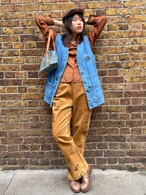 Model wearing oversized 1970s Alpine embroidered denim waistcoat, styled with casual layering