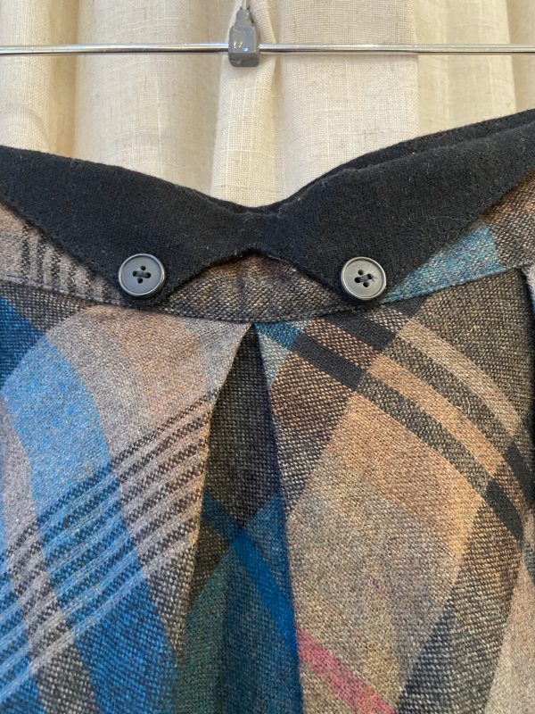 Vintage buttons detail on 1960s plaid A-line skirt, showing plastic zipper and clean stitching.