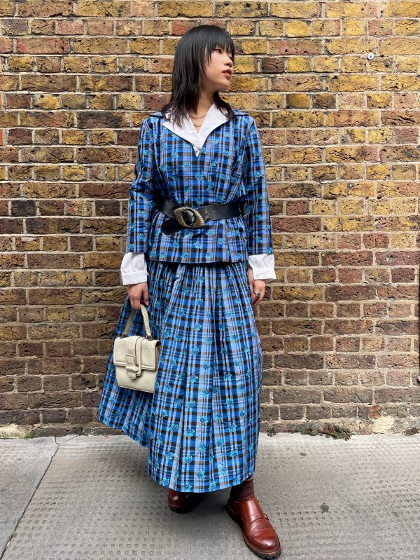 Model wearing early 1980s silk check skirt with matching top, styled with a black belt and white cuffs.