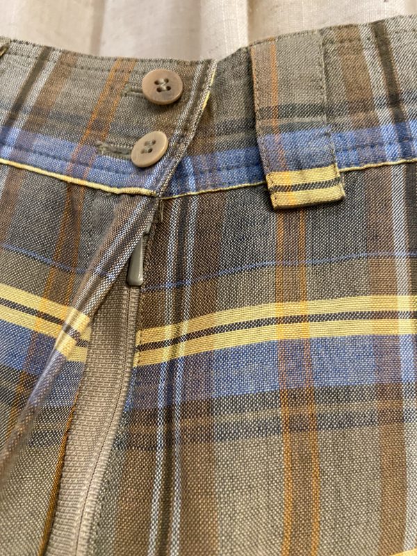 Close-up of the pleated check fabric on a 1970s wool-blend skirt, showing earthy tones and soft texture.