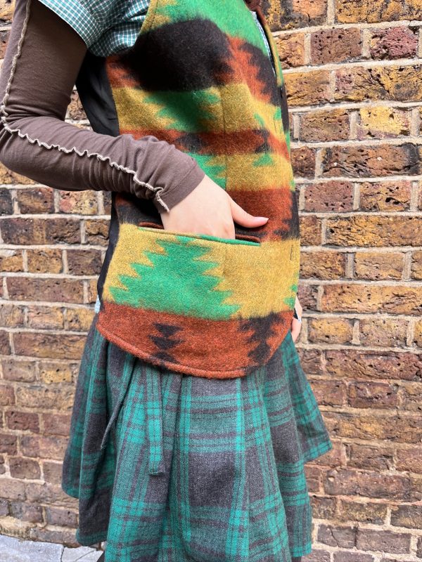 Side view of model in 1990s vintage waistcoat and pleated skirt