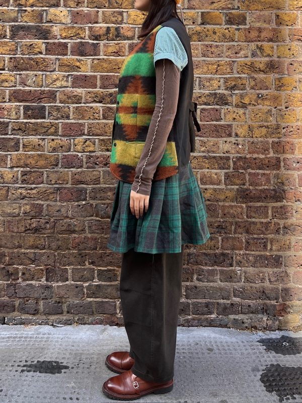 Side view of model in 1990s vintage waistcoat and pleated skirt