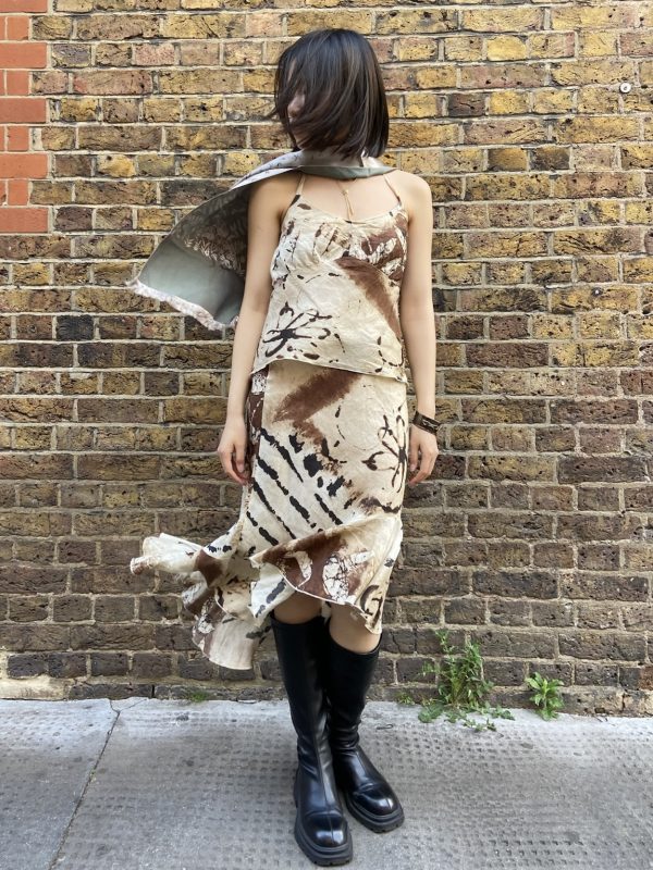 Model wearing early 2000s abstract linen two-piece set in front of brick wall