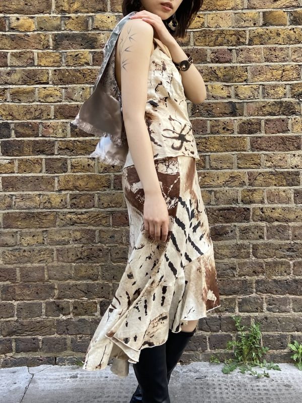 Model wearing early 2000s abstract linen two-piece sett in front of brick wall - side view