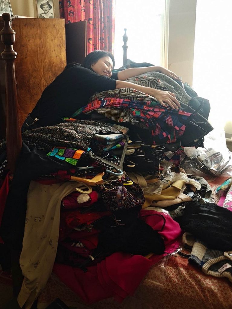 Hugging a huge pile of clothes from a 100-year-old ambassador wardrobe in a sunlit bedroom