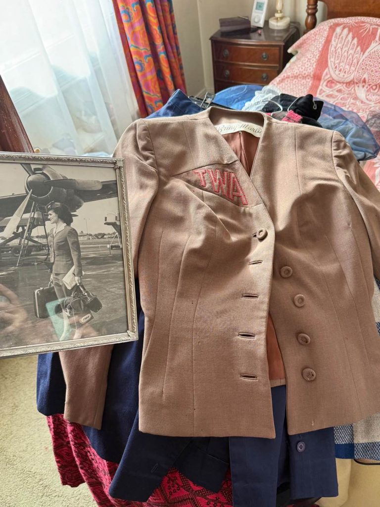 `TWA air hostess uniform jacket from the 100-year-old ambassador wardrobe displayed beside Doreen Willis Bailey’s vintage flight photograph`
