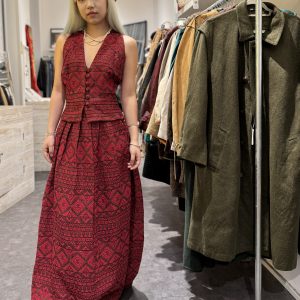 Model wearing 1970s jacquard halterneck set with red folk-weave maxi skirt in vintage boutique